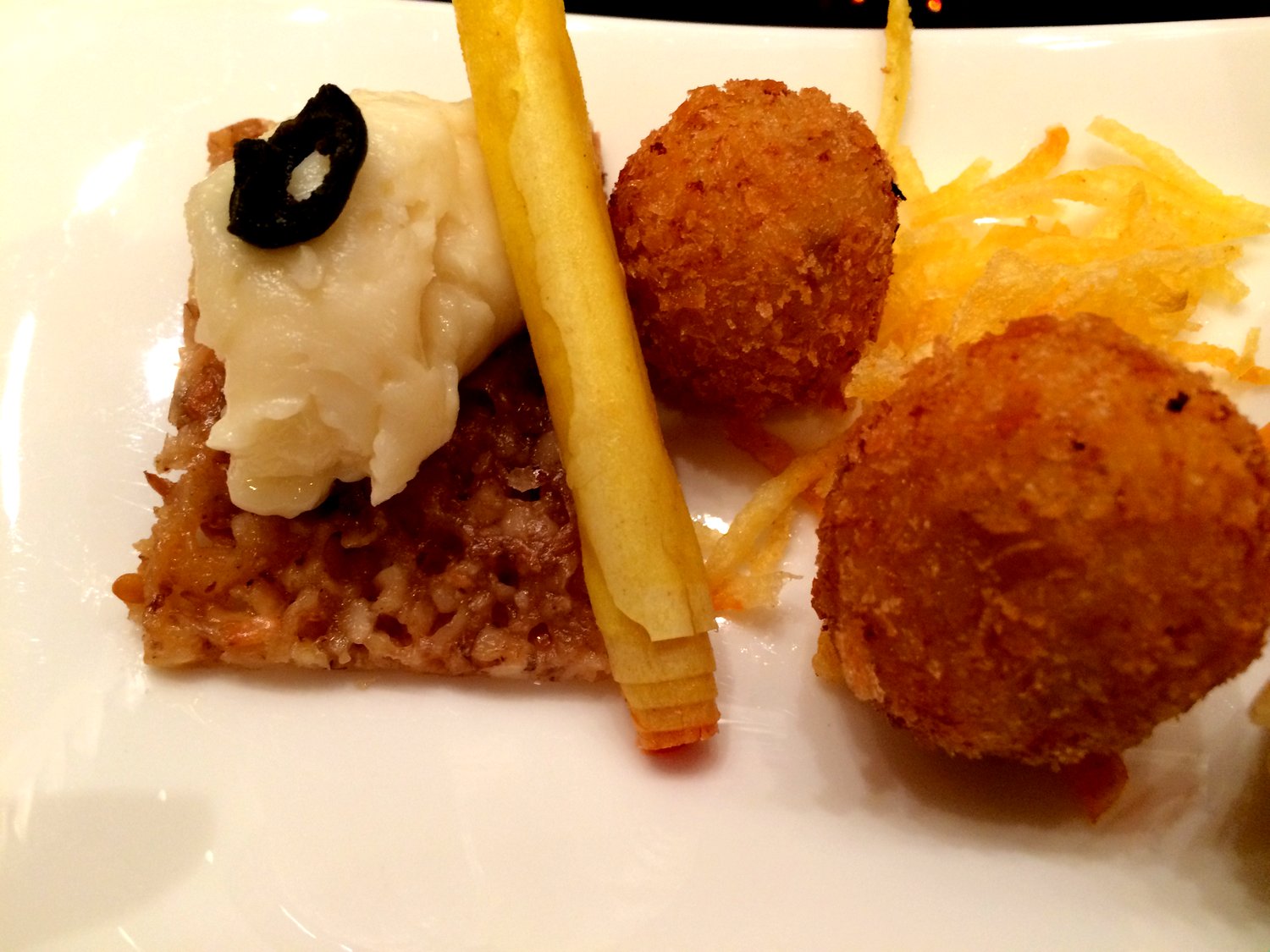 A rice/seed cracker with cheese, a cylinder, and ham croquettes